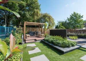 strakke tuin groen grote tegels verhoging overkoepeling zonnedak houten bankjes veranda inspiratie
